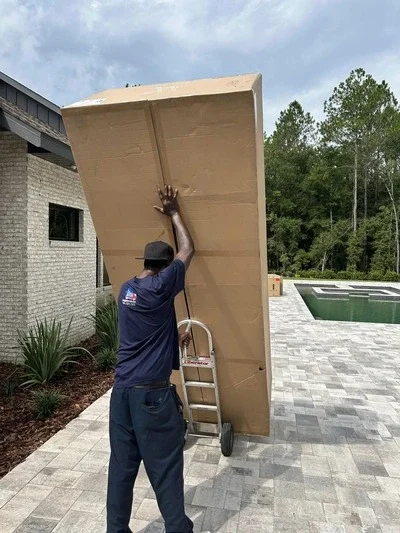 1st Choice Movers team member moving a tall boxed item with a hand truck